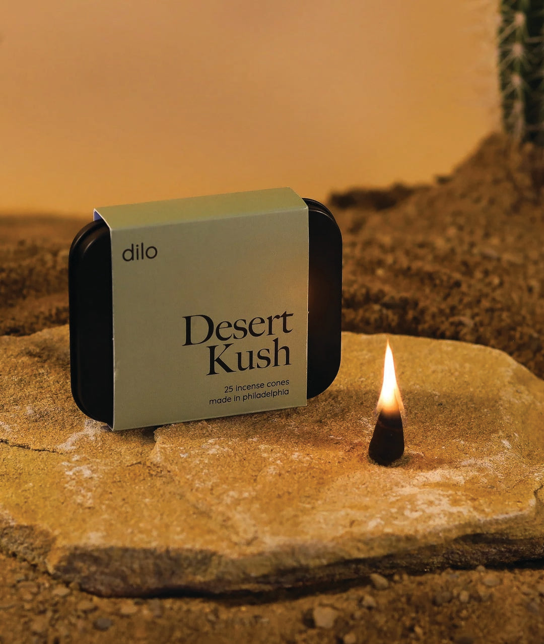 desert kush scented incense cone packaging with lit cone on a stone with desert background
