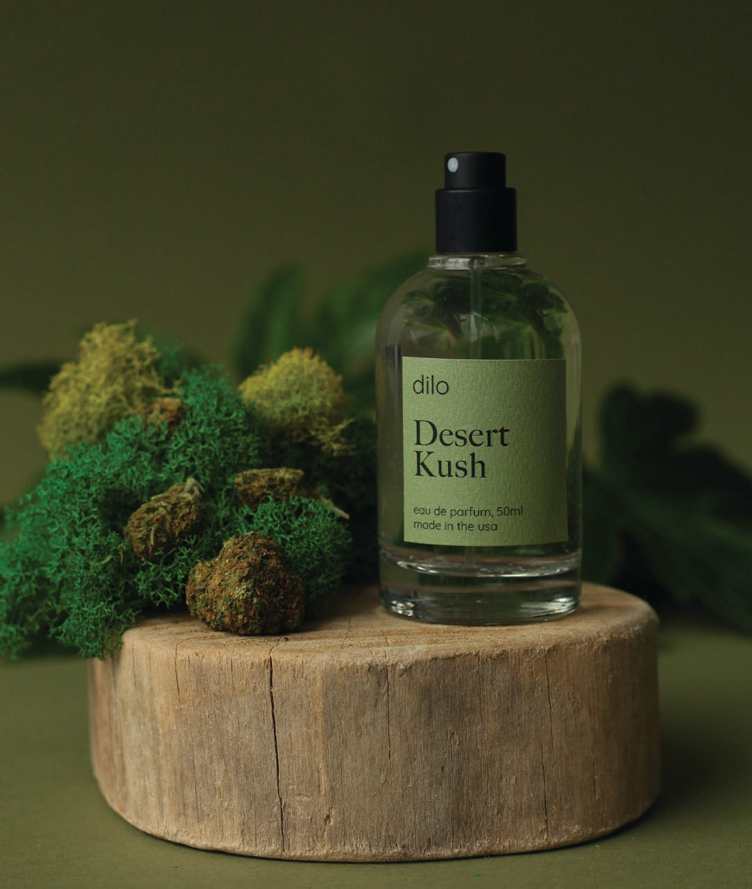 Desert Kush perfume bottle on a wooden platform with greenery in the background