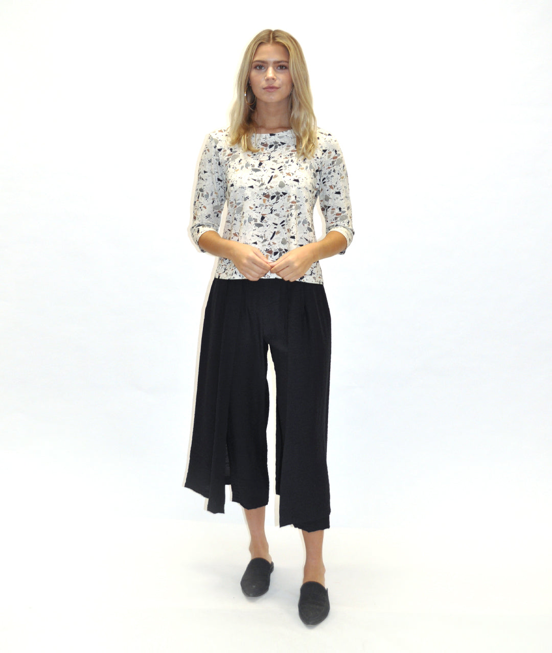 model in a black pant with a draped panel on either side, worn with a fitting terrazzo print top