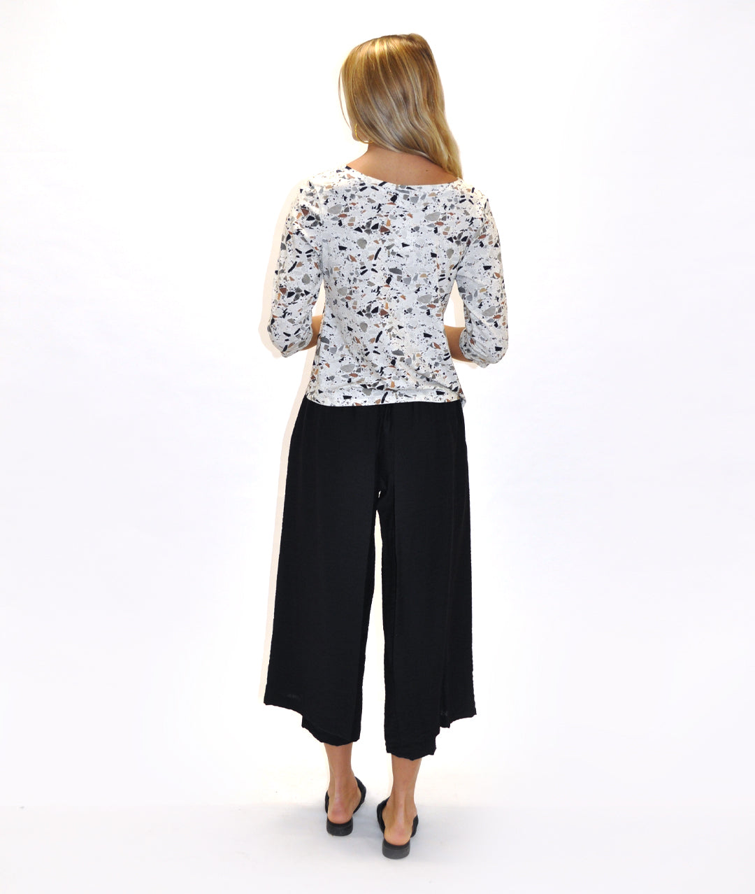 model in a black pant with a draped panel on either side, worn with a fitting terrazzo print top