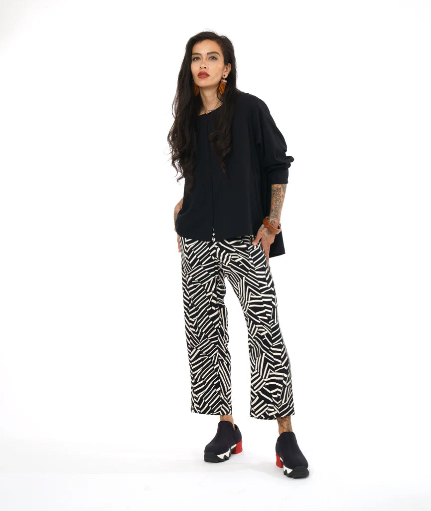 model wearing black top with black and white design pants and sneakers