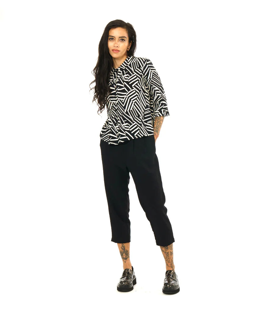 model wearing black and white design button up 3/4 sleeve top with black pants and loafers