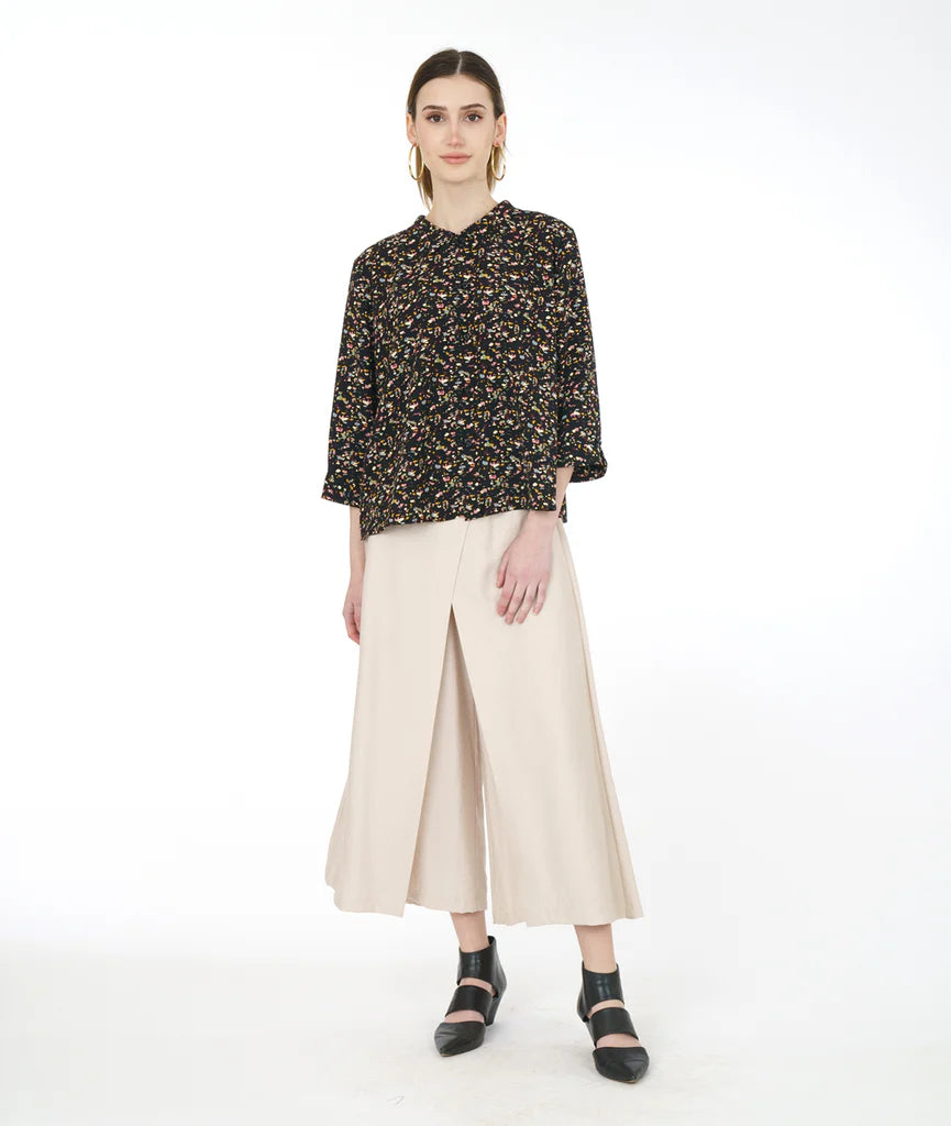 model wearing black terrazzo print top with double sets of "twin" buttons down the front, easy a-line shape and straight hem. Sleeves are 3/4 sleeve with open cuff. paired with pearl color pants and black shoes.