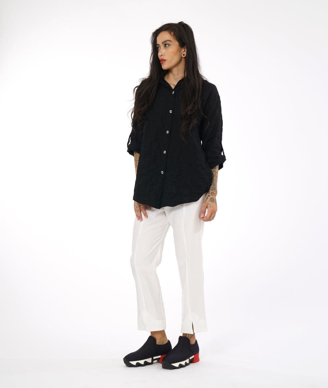 model in a white straight cut pant with a black button down blouse with rolled sleeves