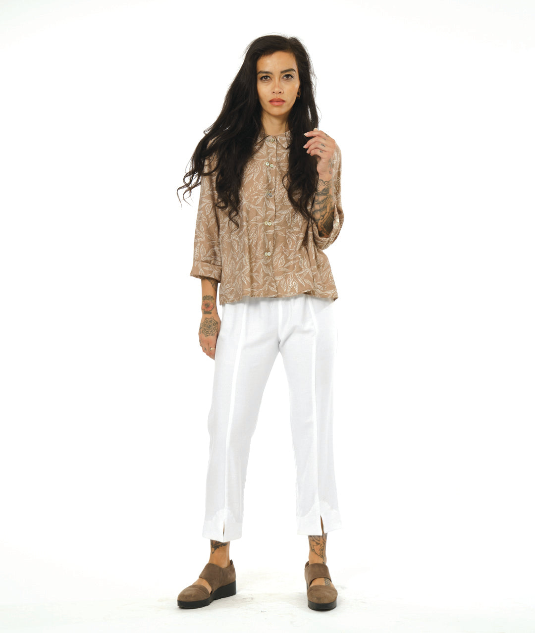 model wearing light brown button up top with white pants that have slits at ankle, paired with brown shoes