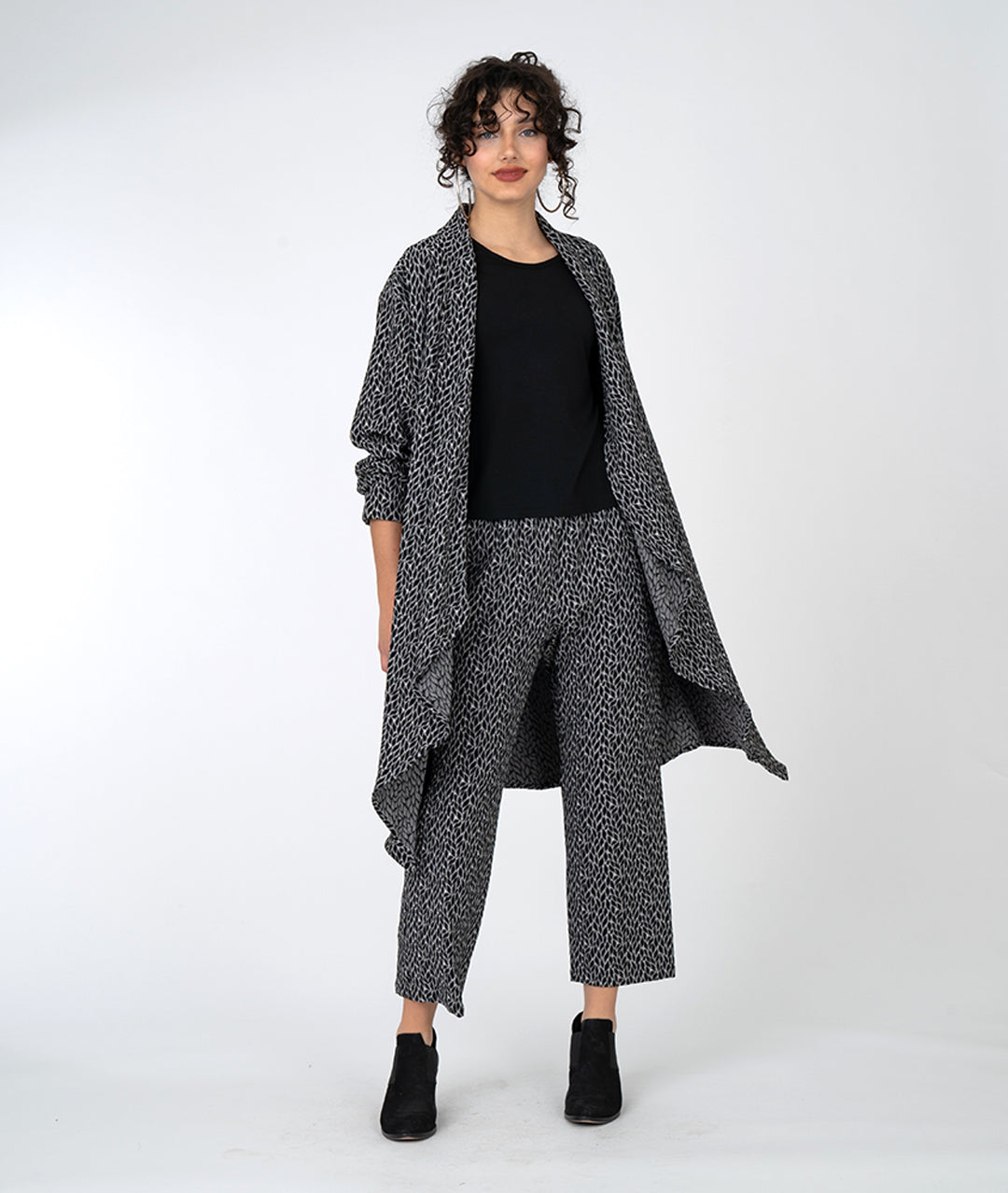 model in a black and grey leaf print straight leg pant, with a matching duster cardigan and a black tee
