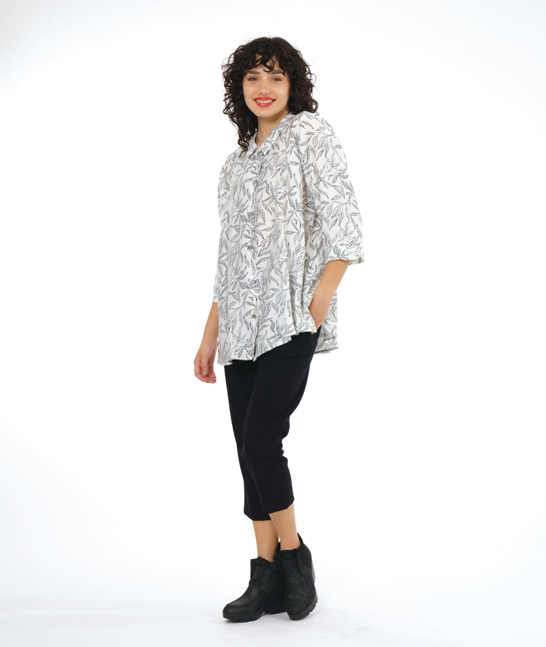 model in a slim black cropped pant, worn with a white button down blouse with a twinbutton detail, 3/4 sleeves, a long body and a floral print