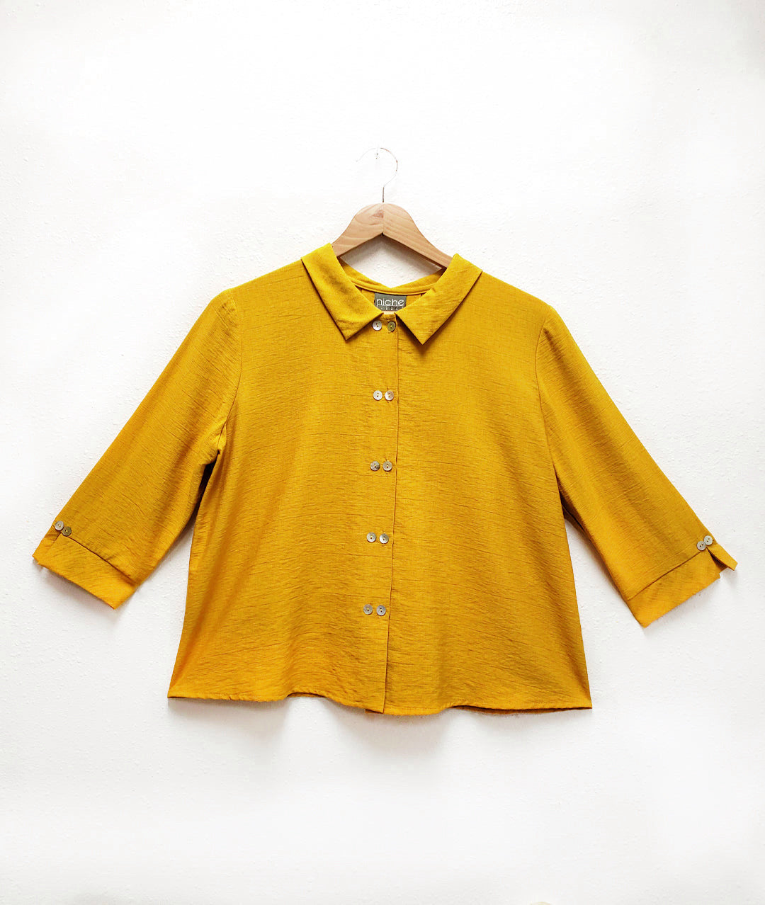 Yellow shirt on a hanger against a white background