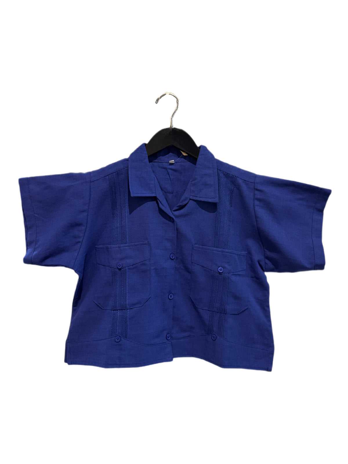A royal blue short-sleeve button-up shirt with two front flap pockets, hanging on a black hanger against a plain white background.