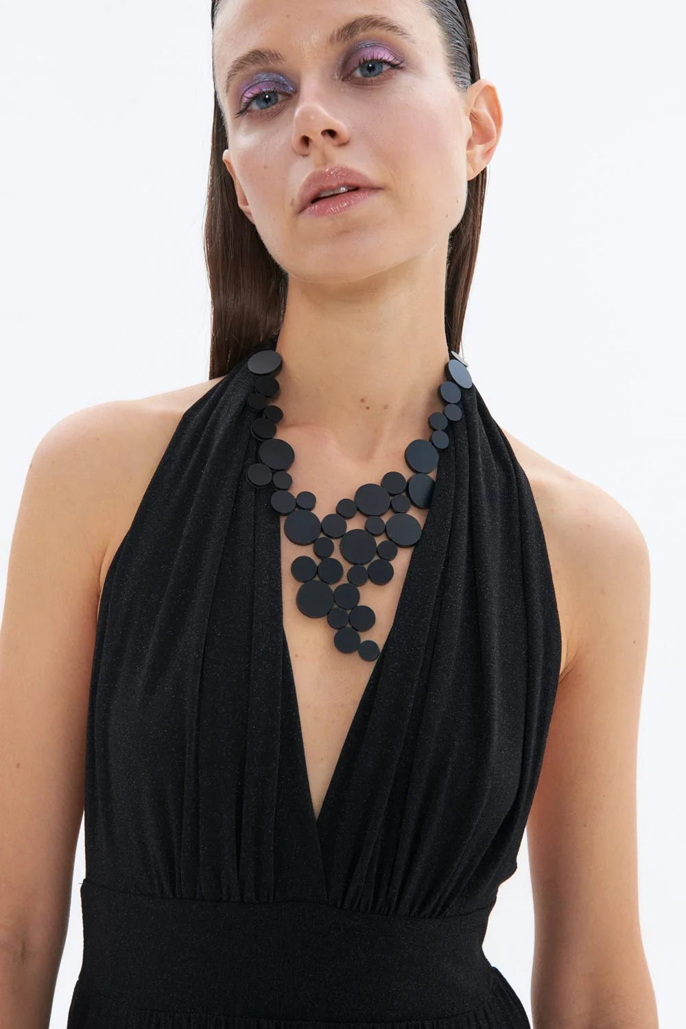 model wearing black circle cluster necklace and bracelet with black halter top against white background