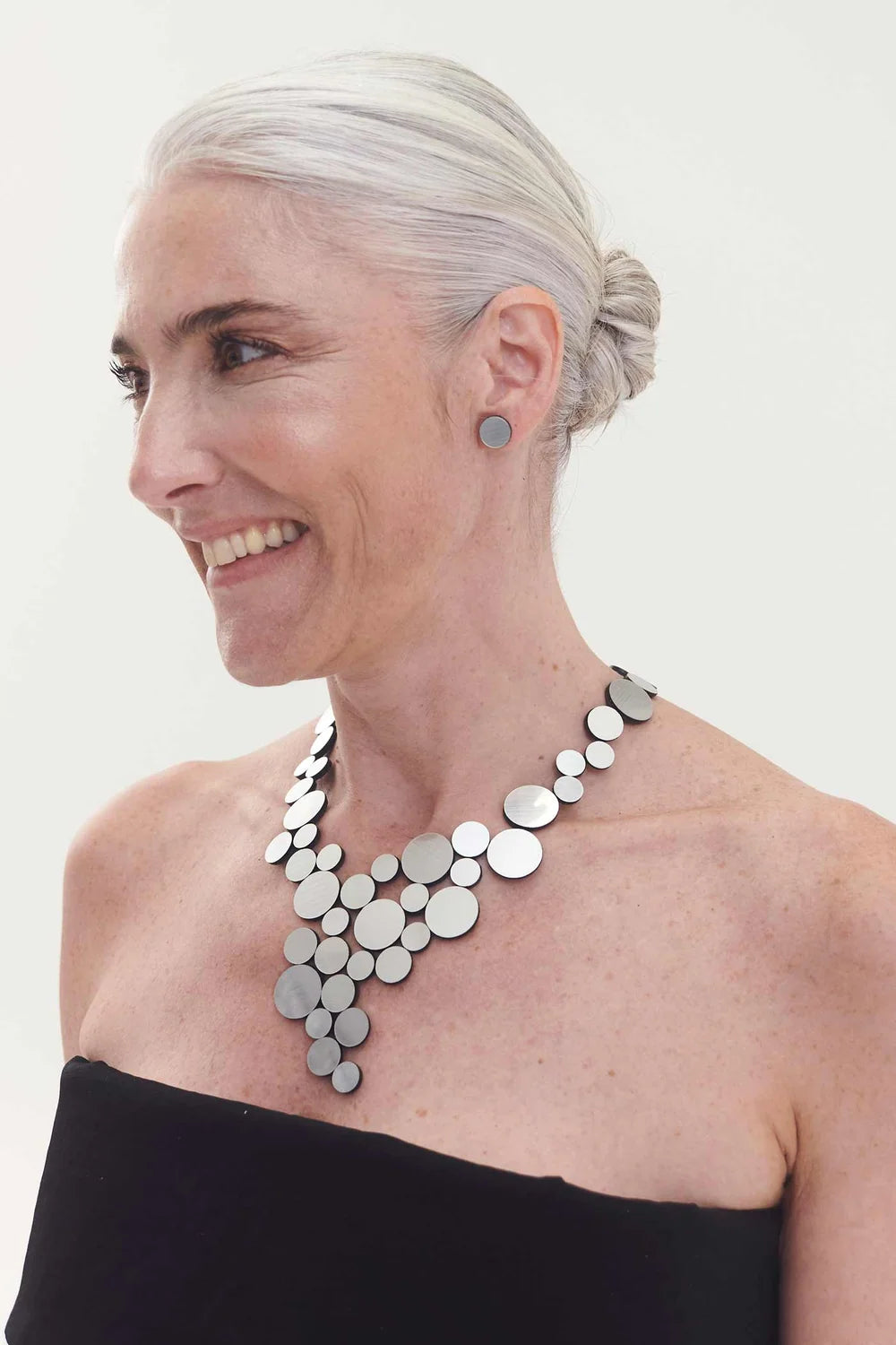 model wearing silver circle cluster necklace with black top against white background