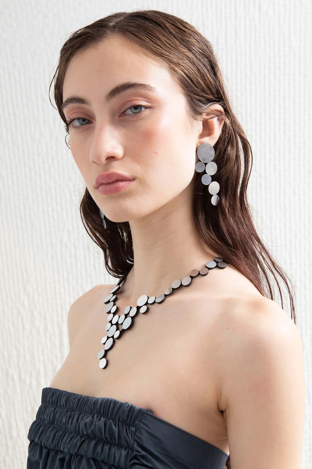 Silver circle cluster earrings and necklace against grey background