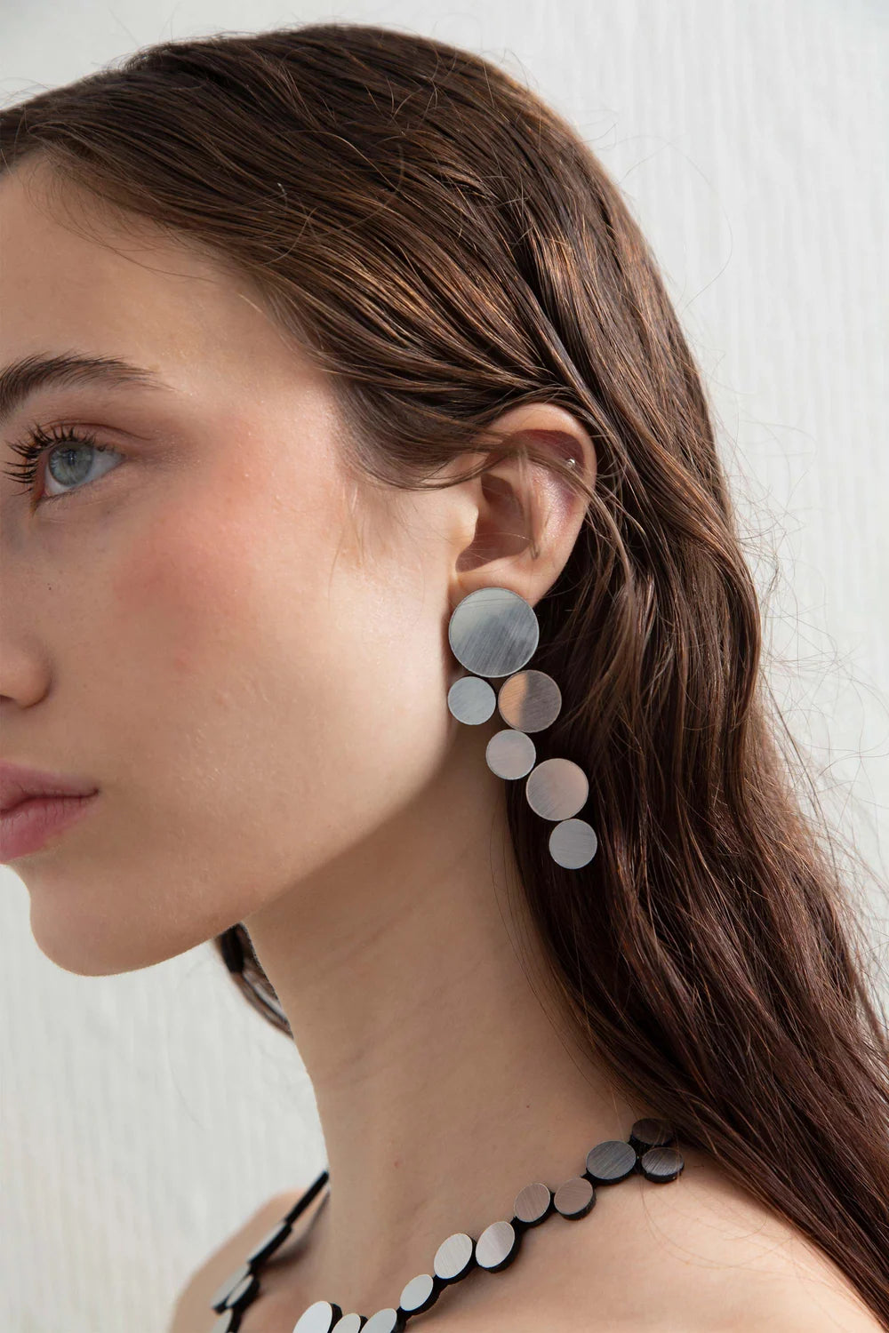 model wearing silver circle cluster earrings against white background