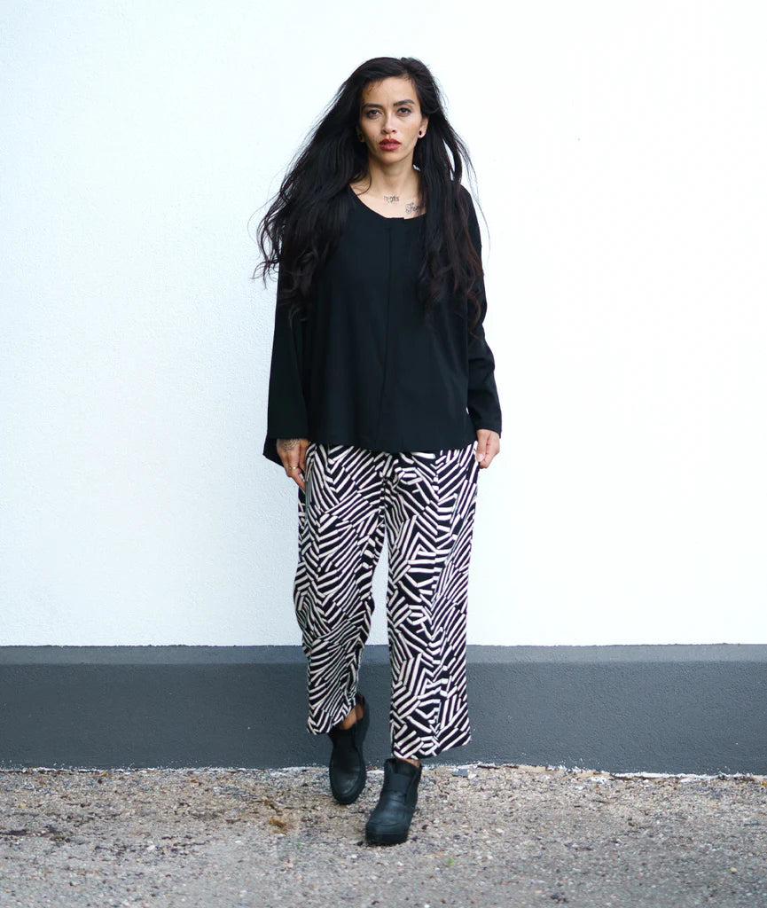 model wearing black top with black and white design pants and short boots