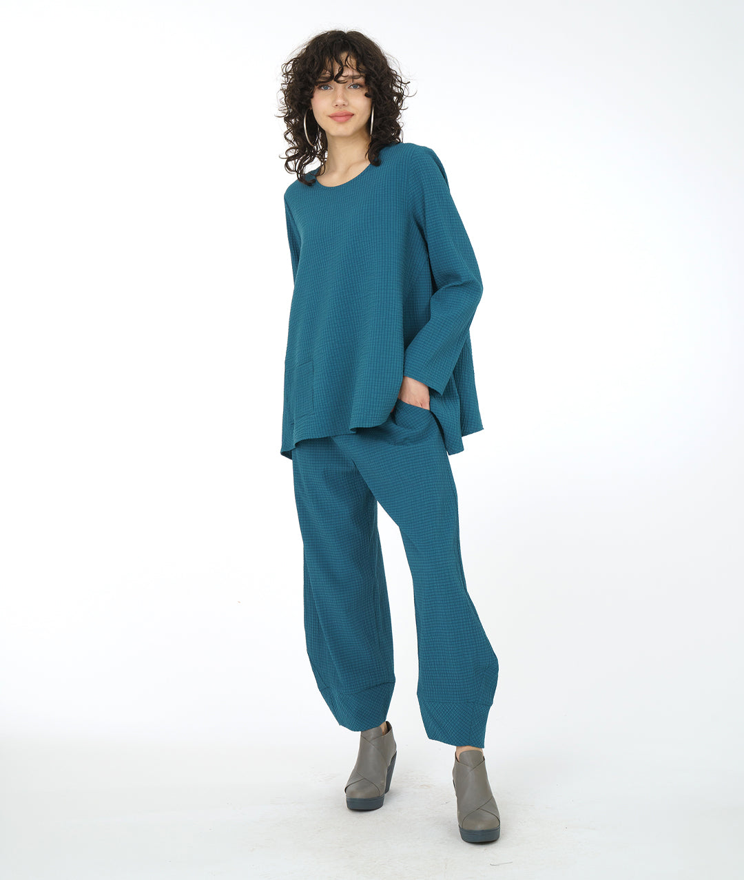 model in a teal flowy top with a matching textured pant with pockets, an elastic waistband, and a tapered cuff at the bottom hem