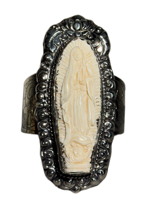 Decorative bracelet with a central carved figure and ornate silver band on a white background