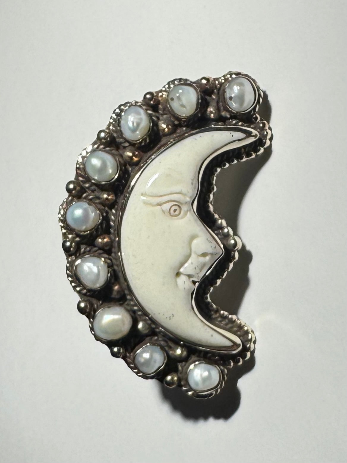 A silver-colored adjustable ring featuring a bone moon design with pearl accents.