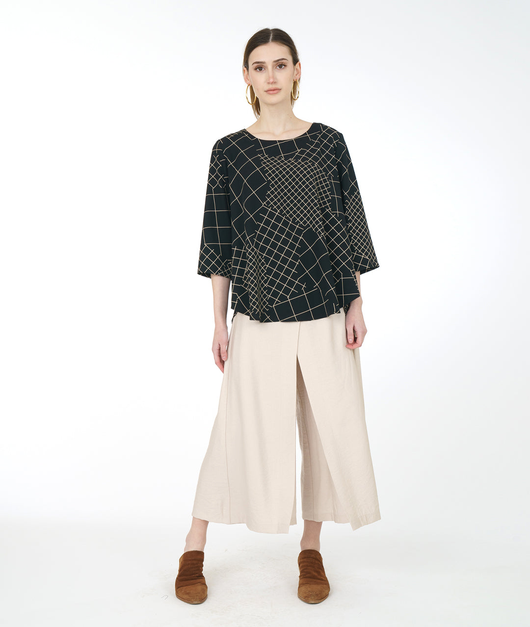 model in a wide leg ivory pant with a black and ivory grid print pull over top with a high-low hem, 3/4 sleeves and a full bodied back