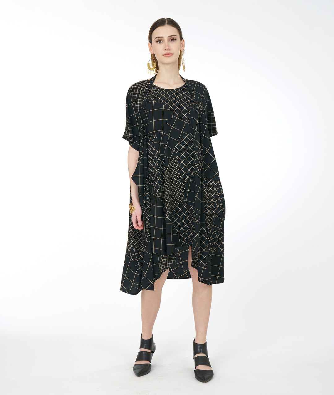 model in a black convertable tunic with an ivory grid pattern. tunic has a band from the hips that can be worn in different styles