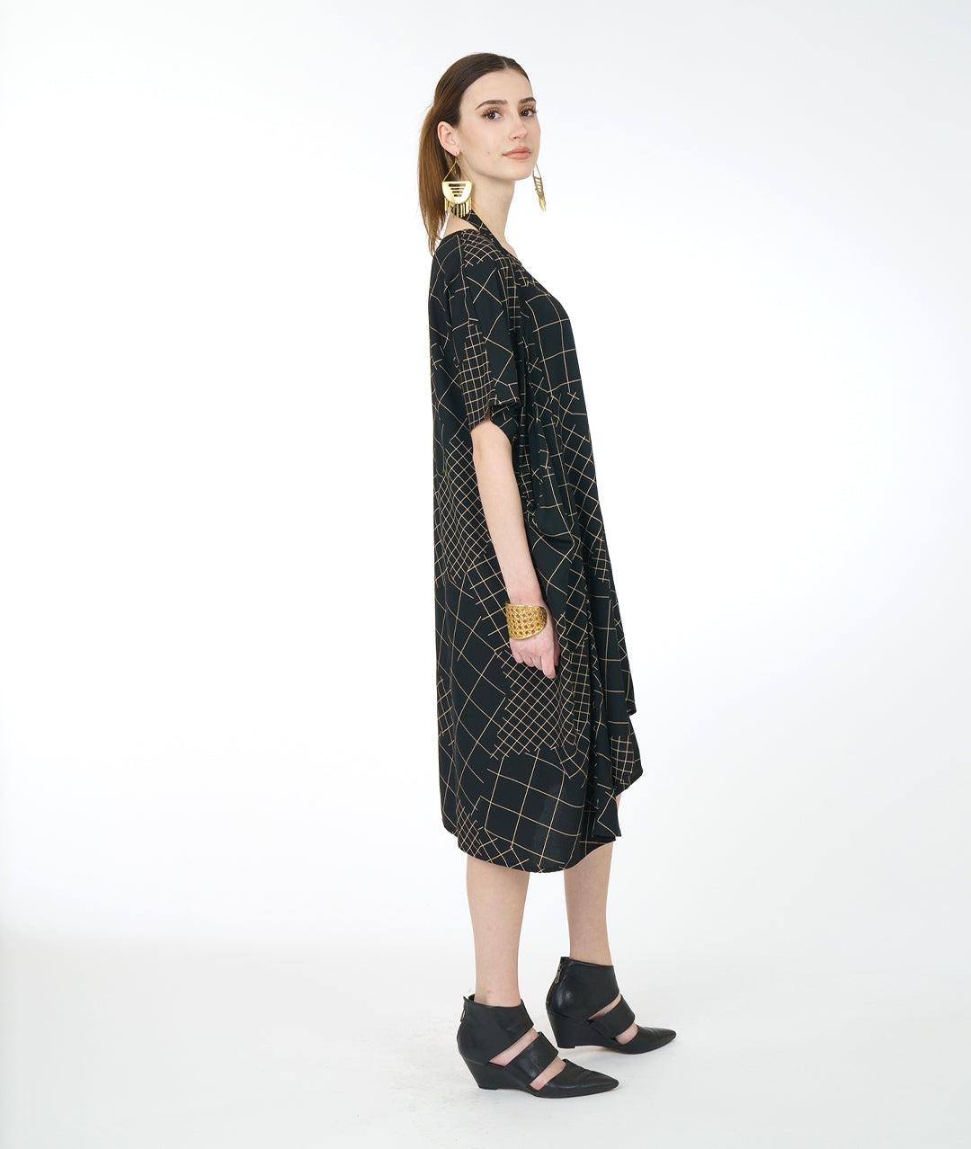model in a black convertable tunic with an ivory grid pattern. tunic has a band from the hips that can be worn in different styles
