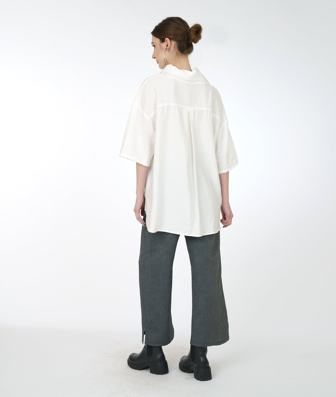 model in a wide leg grey pant with a white cowl neck top with a drop shoulder
