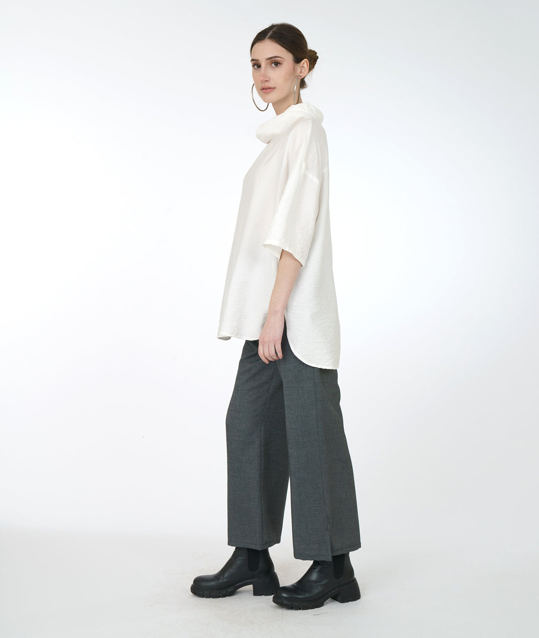 model in a wide leg grey pant with a white cowl neck top with a drop shoulder