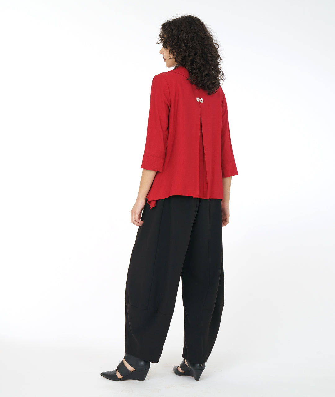 model in a wide leg black pant with a crimson red button down blouse with a 3/4 sleeve and a wide split cuff. blouse has a double button detail and flat collar