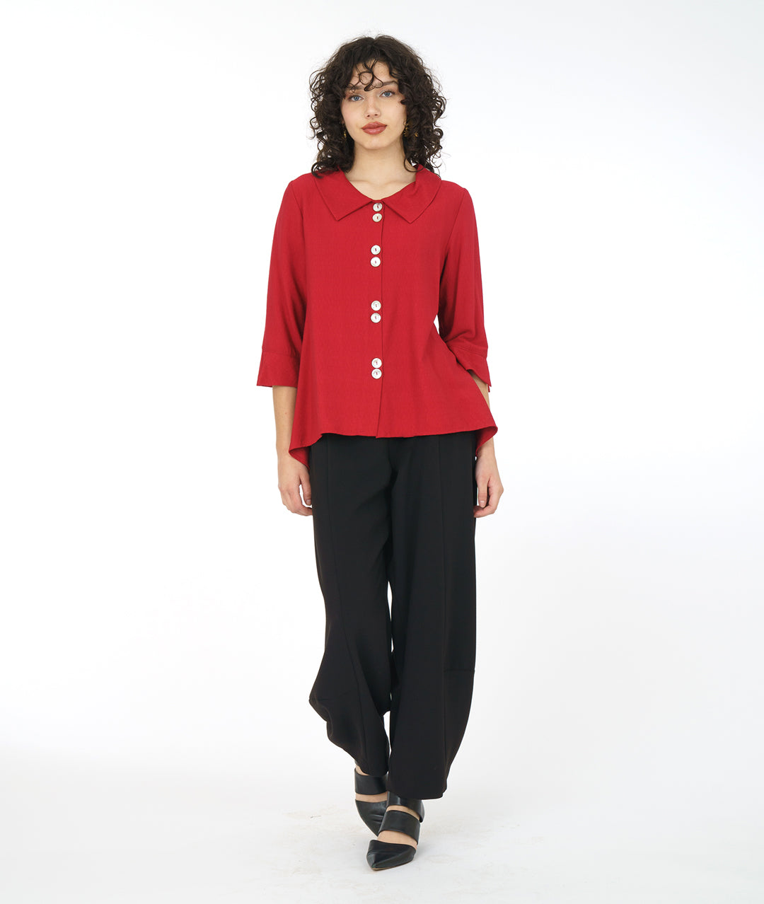 model in a wide leg black pant with a crimson red button down blouse with a 3/4 sleeve and a wide split cuff. blouse has a double button detail and flat collar