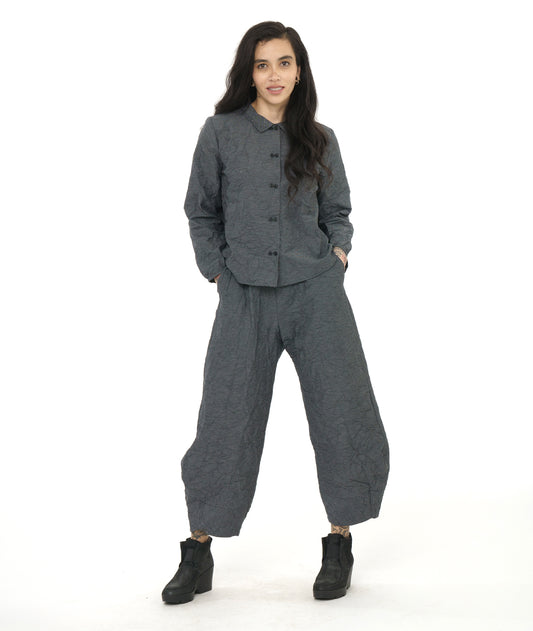 model in a black and grey pinstriped wide leg pant with a tapered ankle, worn with a matching button down blouse with long sleeves gathered at a thin cuff