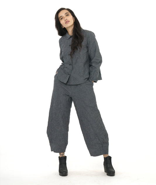 model in a black and grey pinstriped wide leg pant with a tapered ankle, worn with a matching button down blouse with long sleeves gathered at a thin cuff