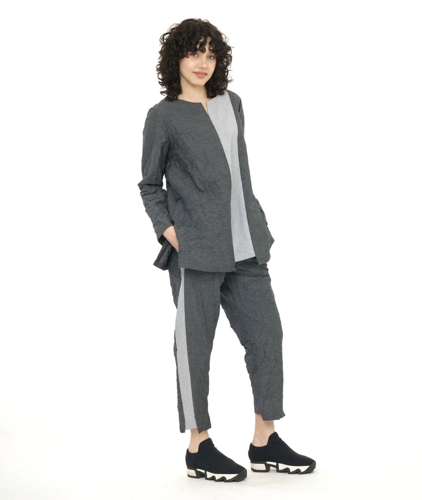 model wearing long sleeve dark grey top and pants with contrasting panels at front center seam and along side of pants with sneakers.