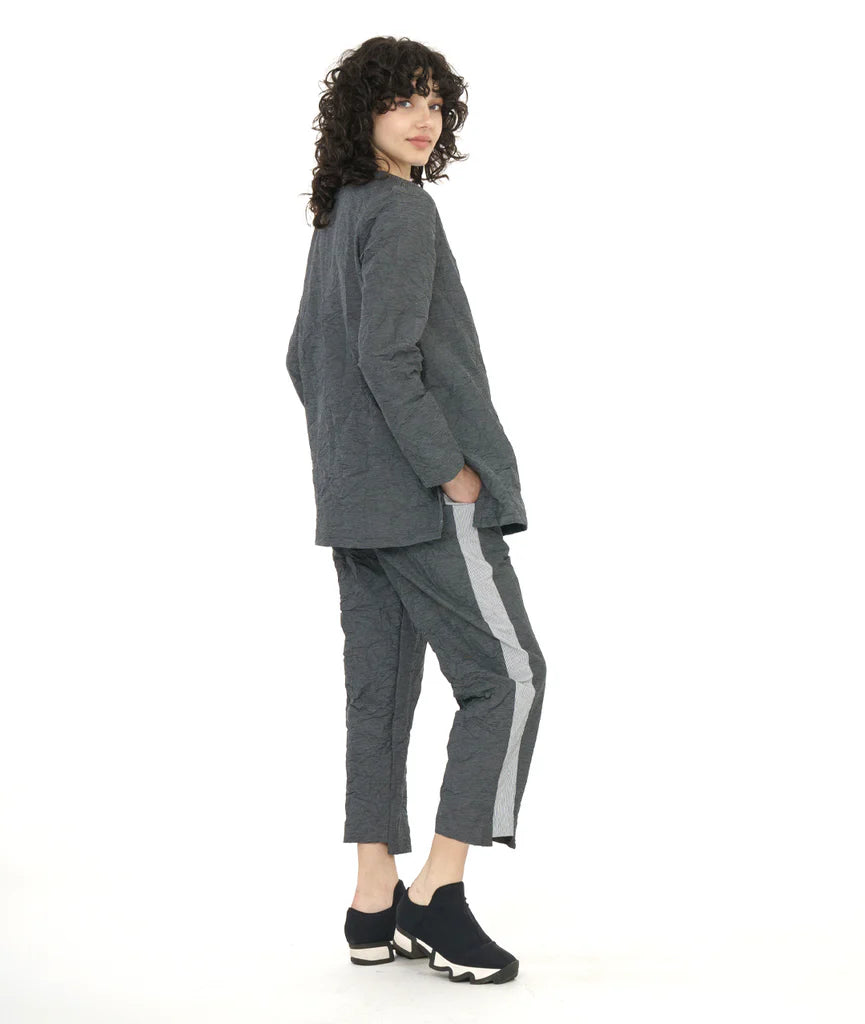 model wearing long sleeve dark grey top and pants with contrasting panels at front center seam and along side of pants with sneakers.