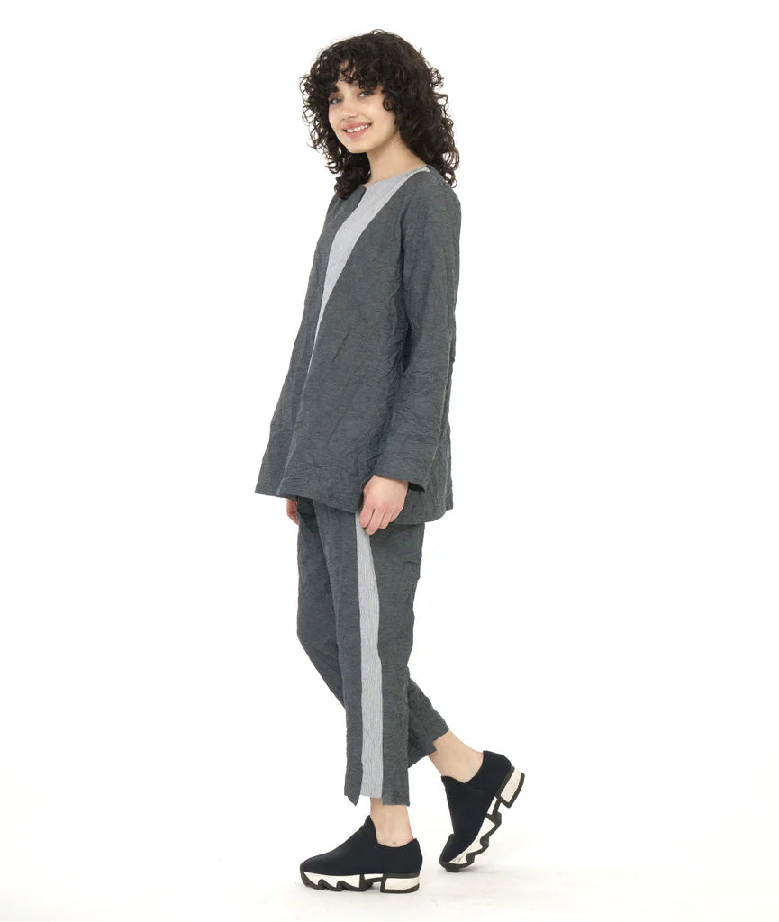 model wearing long sleeve dark grey top and pants with contrasting panels at front center seam and along side of pants with sneakers.