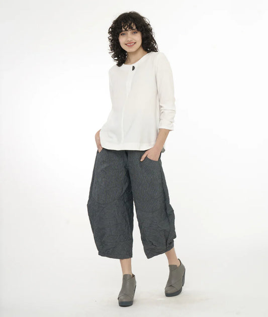 model wearing white 3/4 sleeve top with single button, dark grey wide leg pants tapered at ankles and deep pockets with grey shoes.