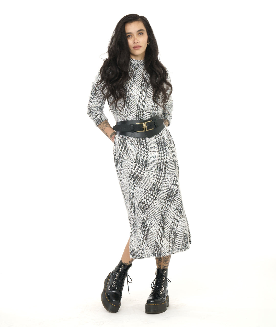 model in a black and white wavy plaid print dress with long sleeves and a split at either side of the bottom hem