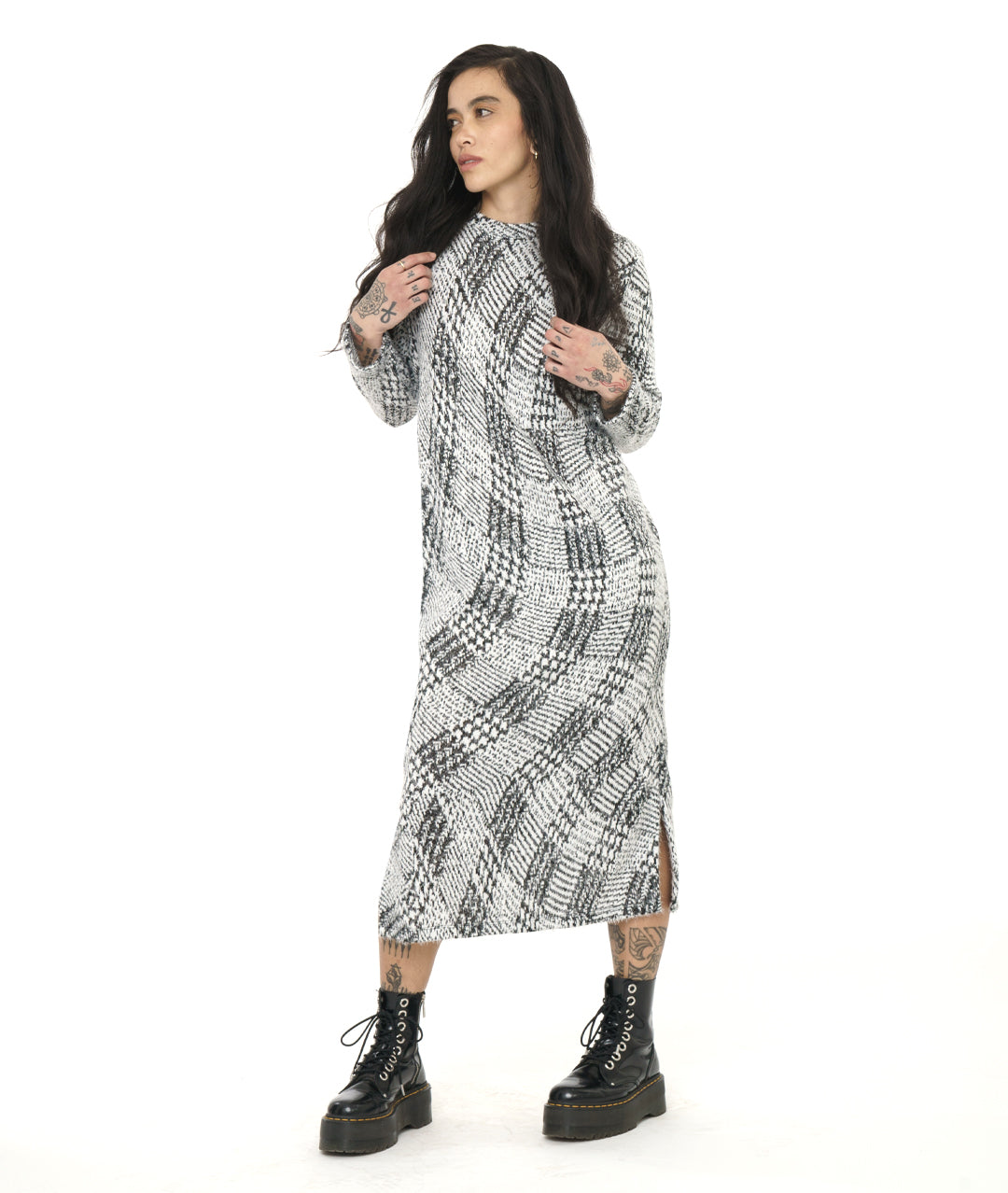 model in a black and white wavy plaid print dress with long sleeves and a split at either side of the bottom hem