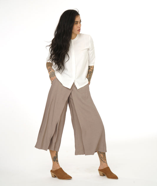 Woman wearing a white blouse and beige wide-leg pants on a white background