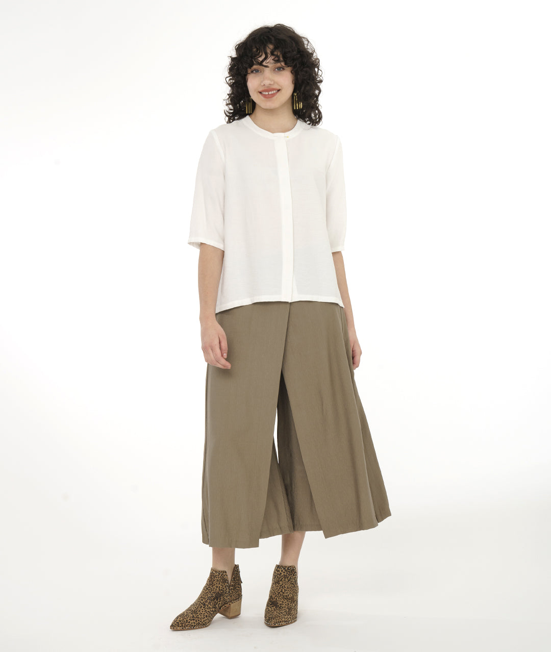 Woman wearing a white top and beige wide-leg pants on a white background