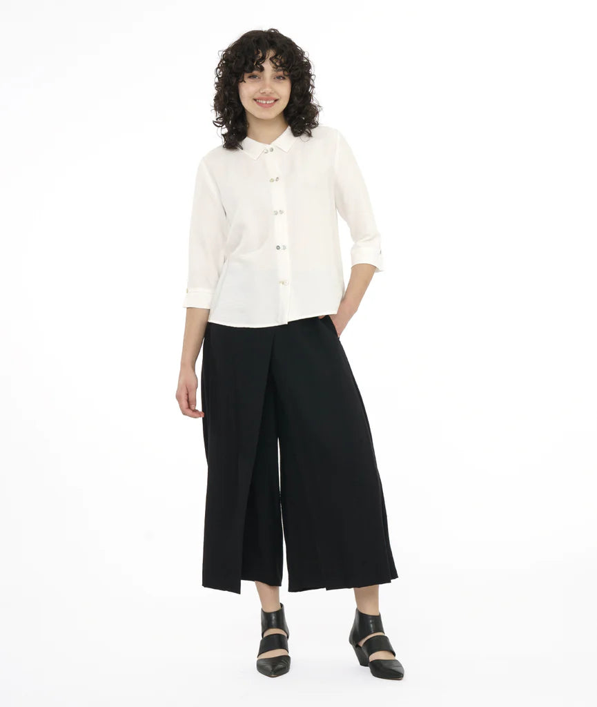 model with a white button up shirt with a black pant in front of a white back ground