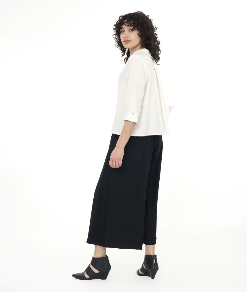 model with a white button up shirt with a black pant in front of a white back ground