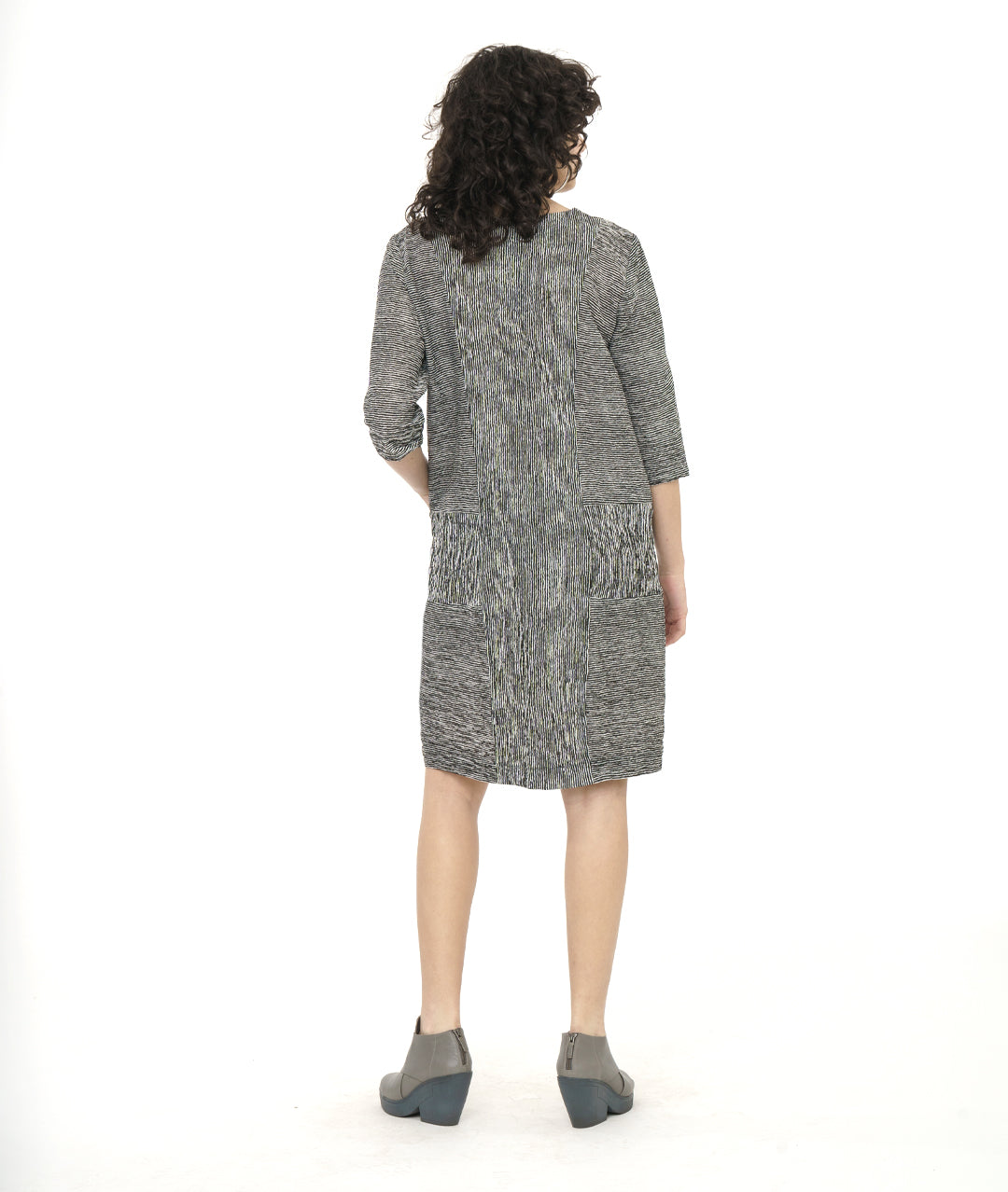 model in a black and white pinstriped shift dress with 3/4 sleeves, princess seams, and hip pockets. dress has contrasting panels and is knee length