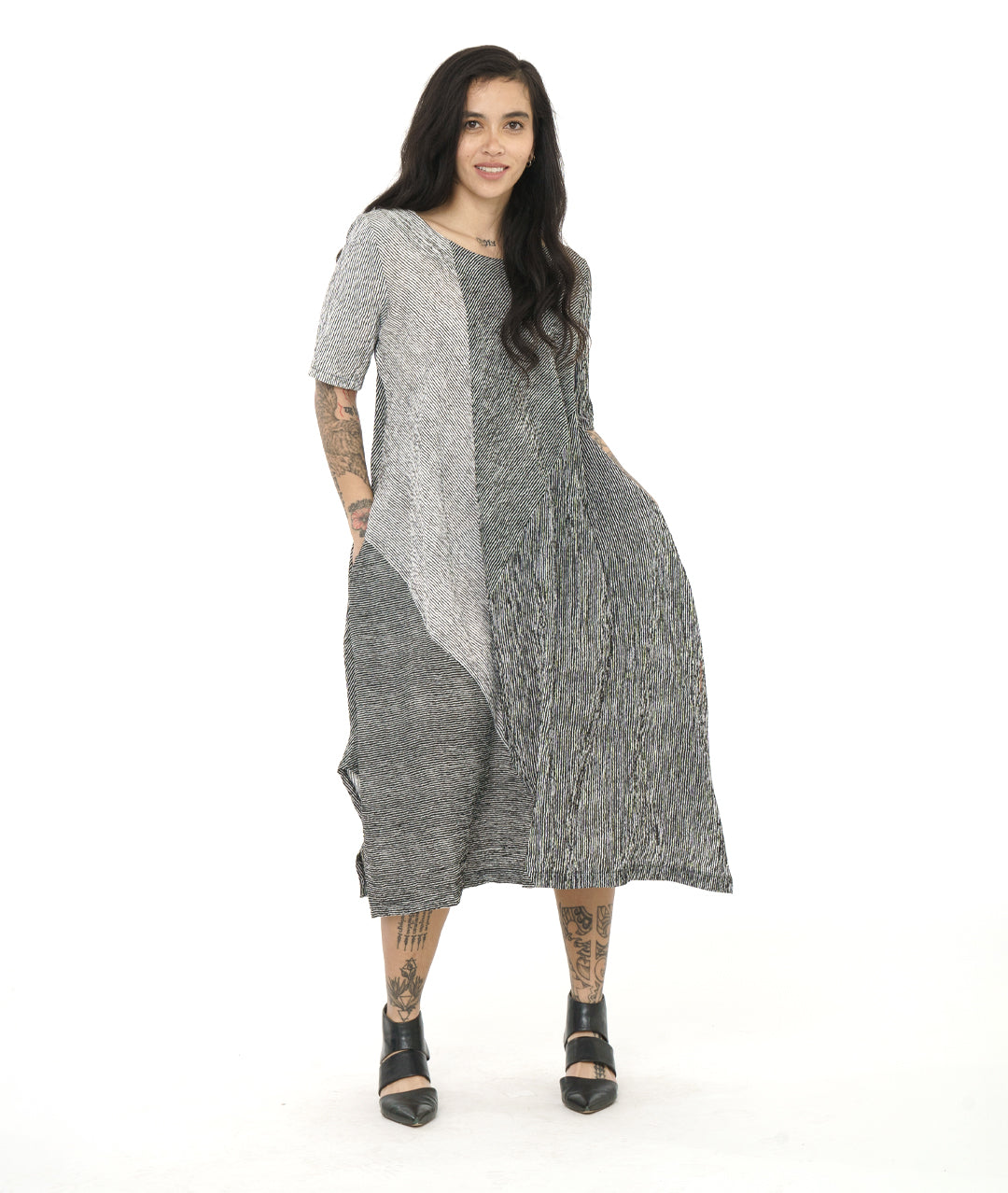 model in a black and white striped dress with contrasting panels and tucks on the sides