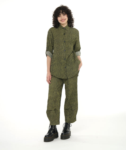 model in a green and black stripe blouse with rolled sleeves, worn with a matching pant with a tulip shape made from pleating below the knee