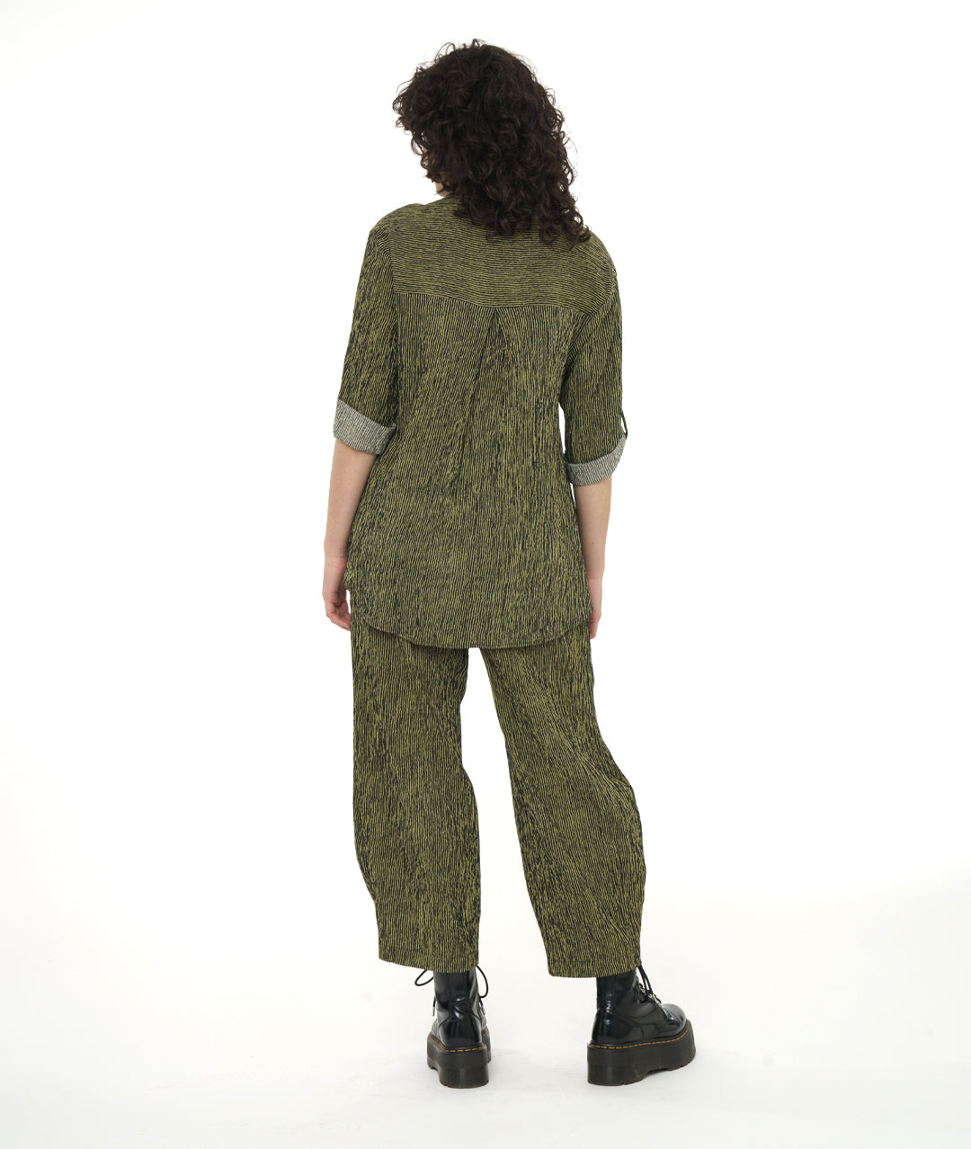 model in a green and black stripe blouse with rolled sleeves, worn with a matching pant with a tulip shape made from pleating below the knee