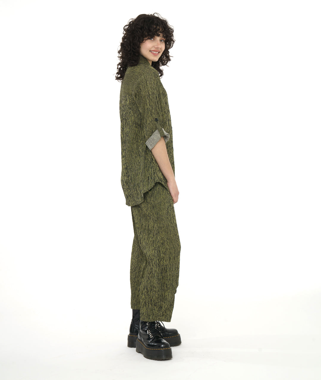 model in a green and black stripe blouse with rolled sleeves, worn with a matching pant with a tulip shape made from pleating below the knee