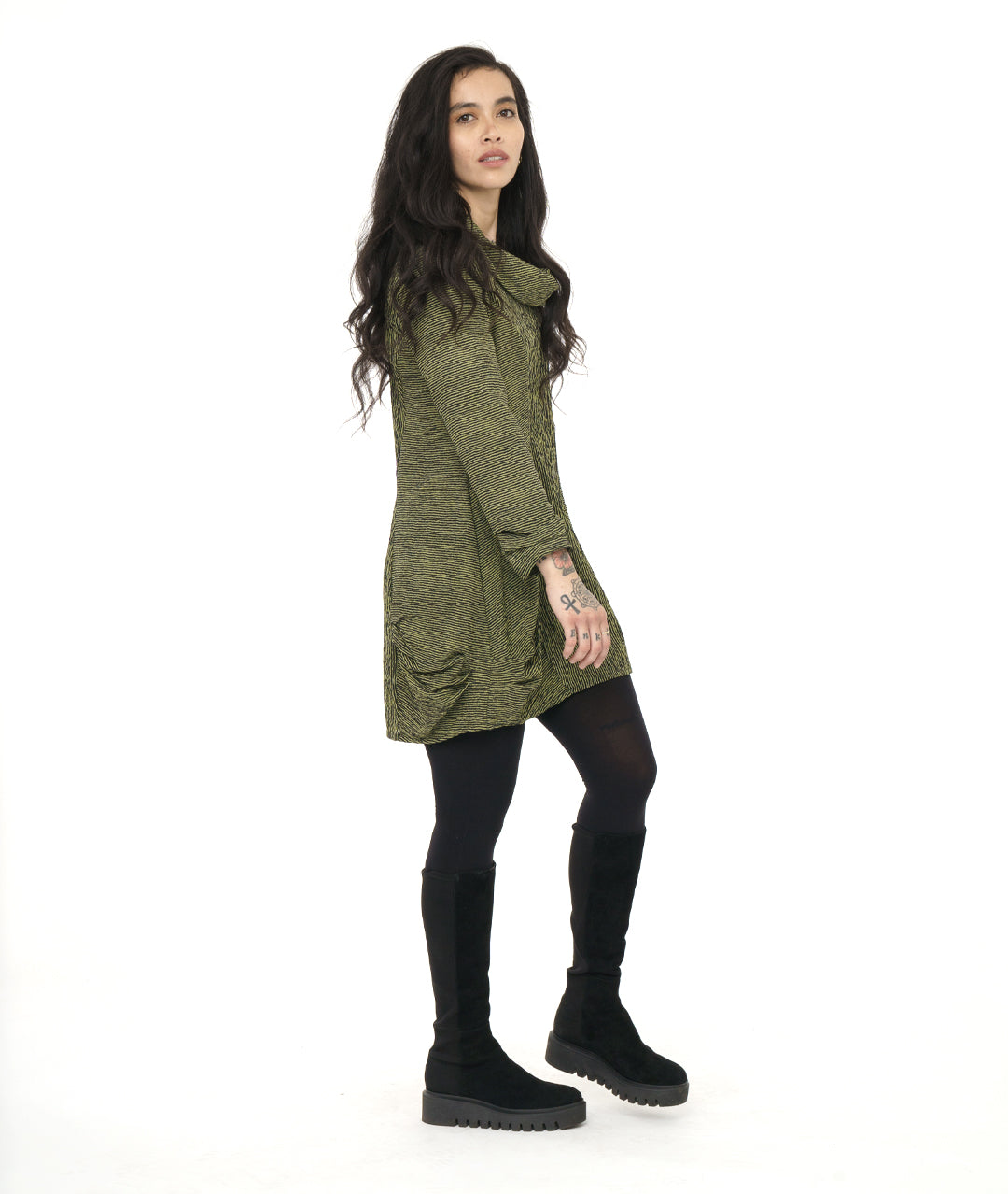 model in a green and black striped tunic with princess seams, a large cowl neck, long sleeves and pleating at the hips