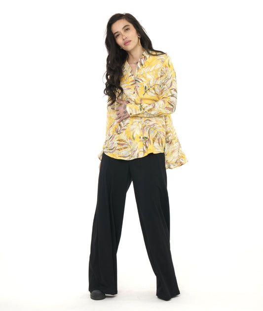 model in a wide leg black pant with a yellow floral print blouse with a rounded hem, dipping lower in the back