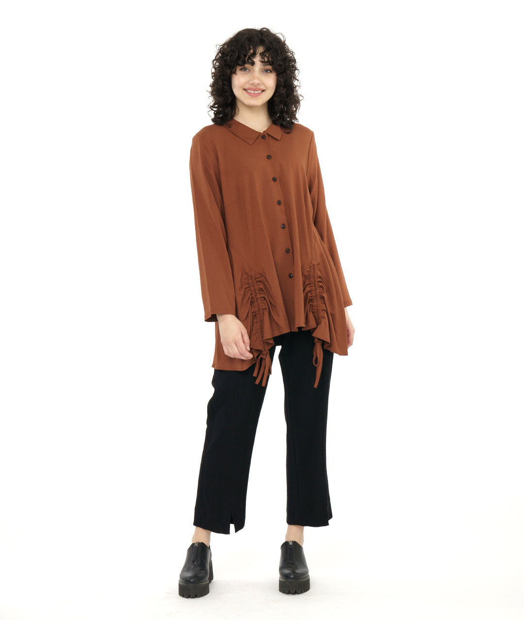 model in a straight leg black pant with a rust color button down blouse with a gathered detail at each front hip