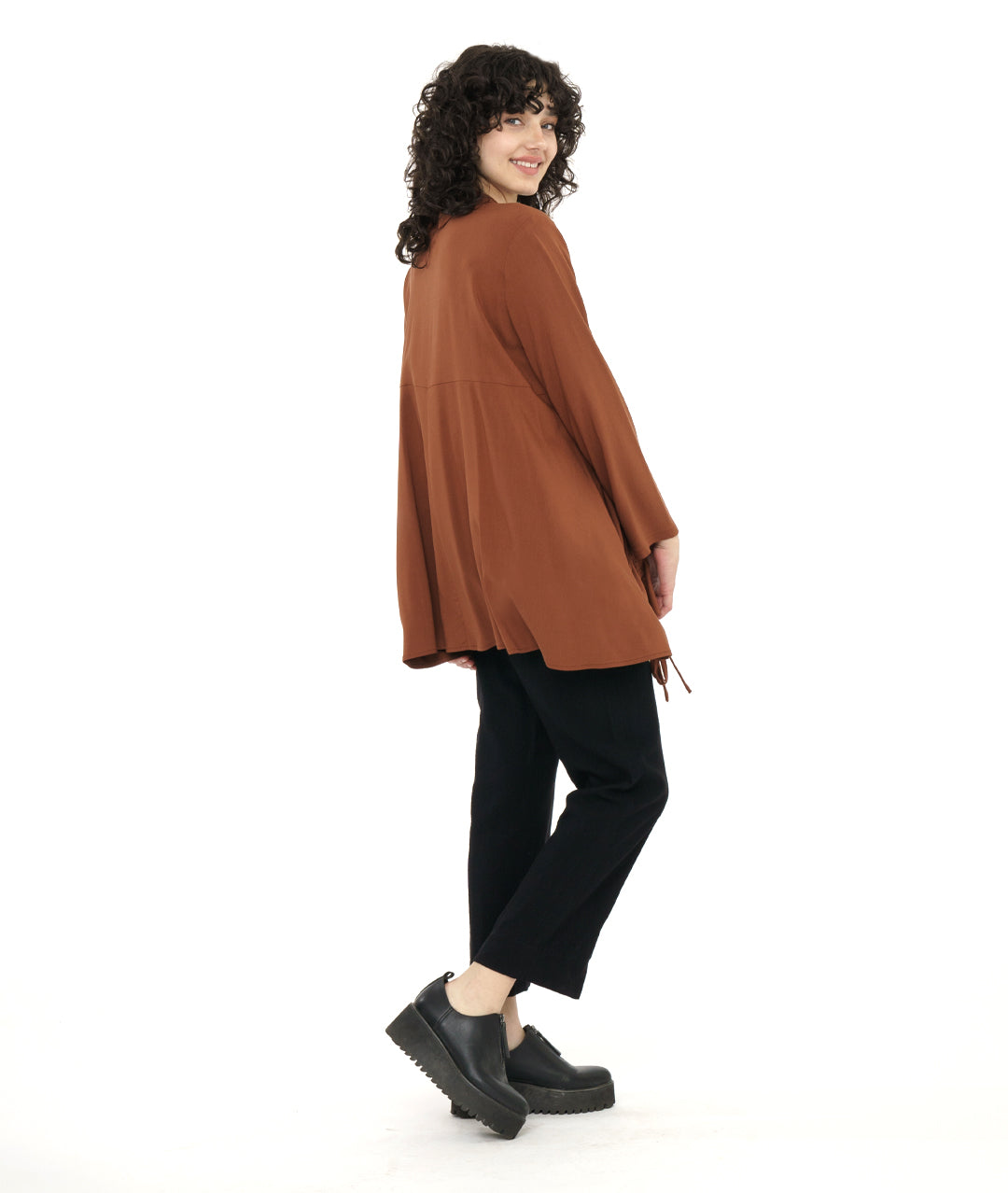 model in a straight leg black pant with a rust color button down blouse with a gathered detail at each front hip