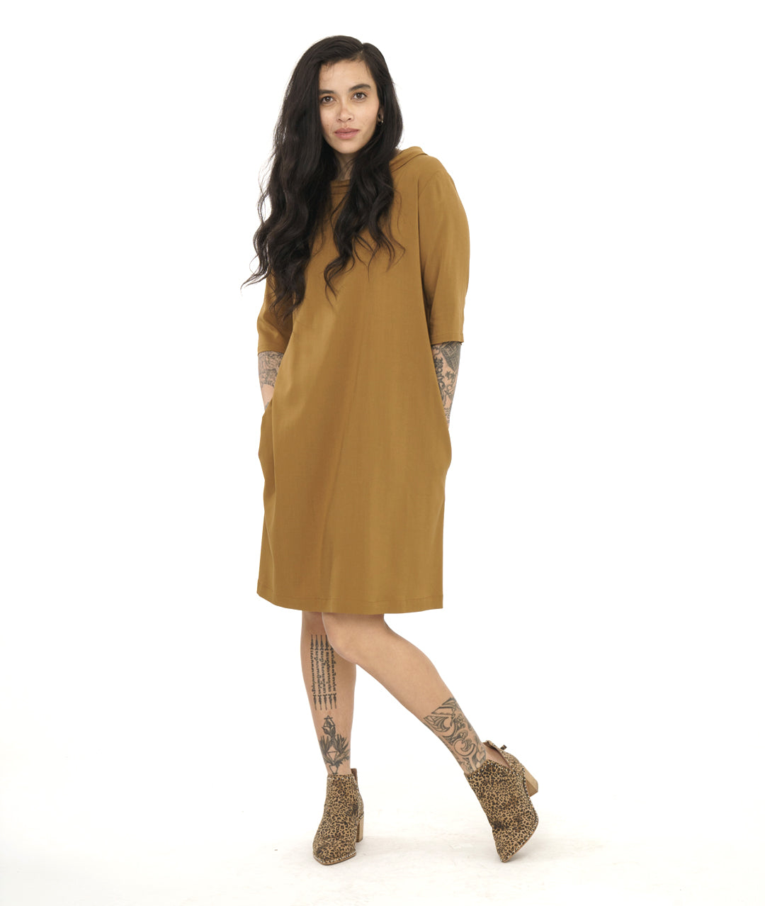 model in an ochre color shift dress with 3/4 sleeves and a cowl collar